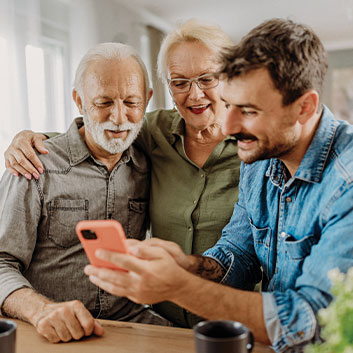 Adult son showing older parents planned giving benefits on his phone. Read about Gifts That Pay You Income Adult son showing older parents planned giving benefits on his phone. Read about Gifts That Pay You Income